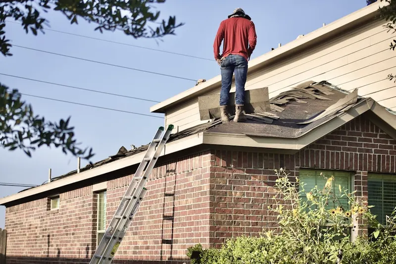 Professional roofer working on a residential roof in DeWeese